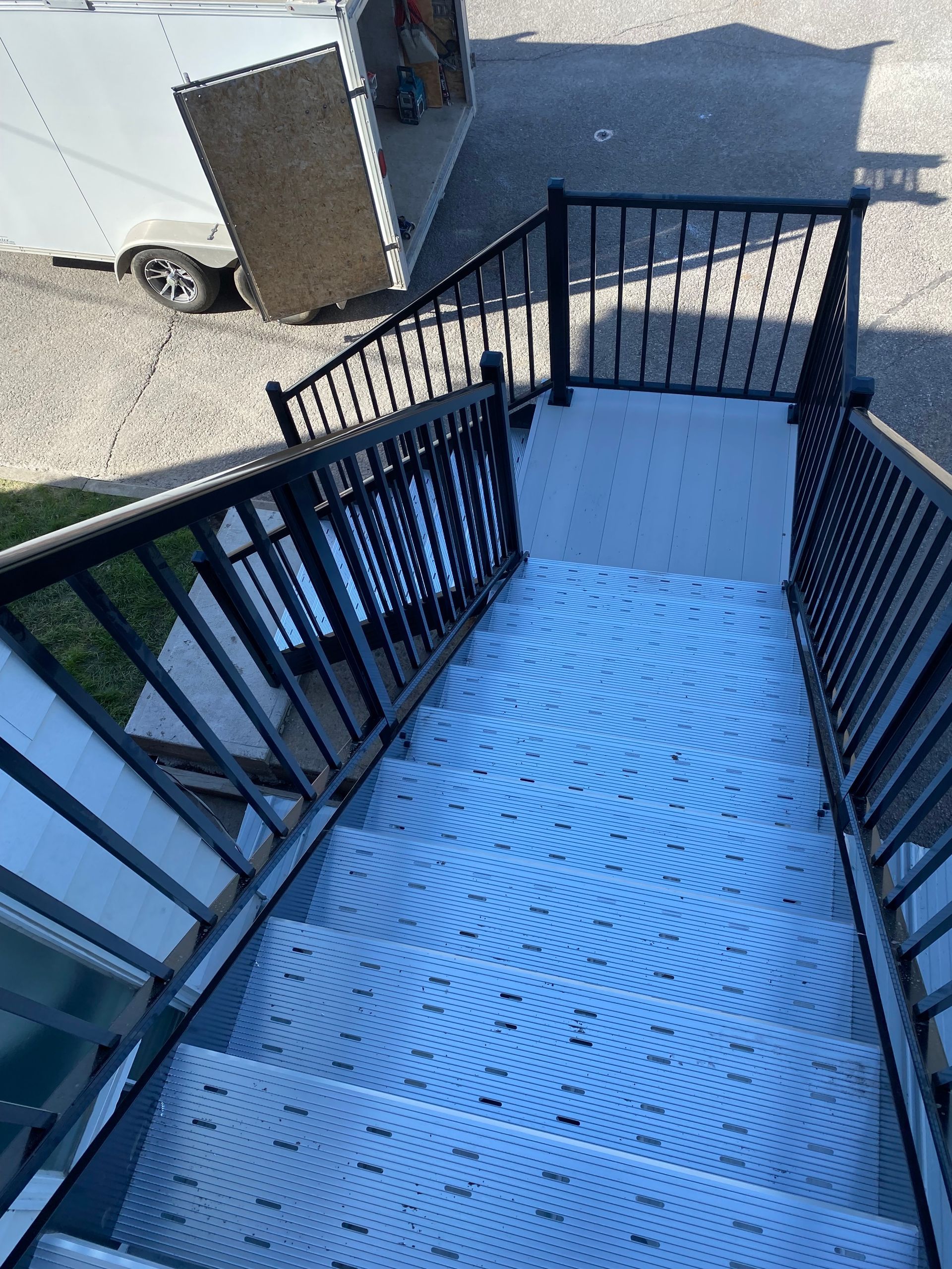 Un ensemble d'escaliers avec une rampe noire menant à un bâtiment.