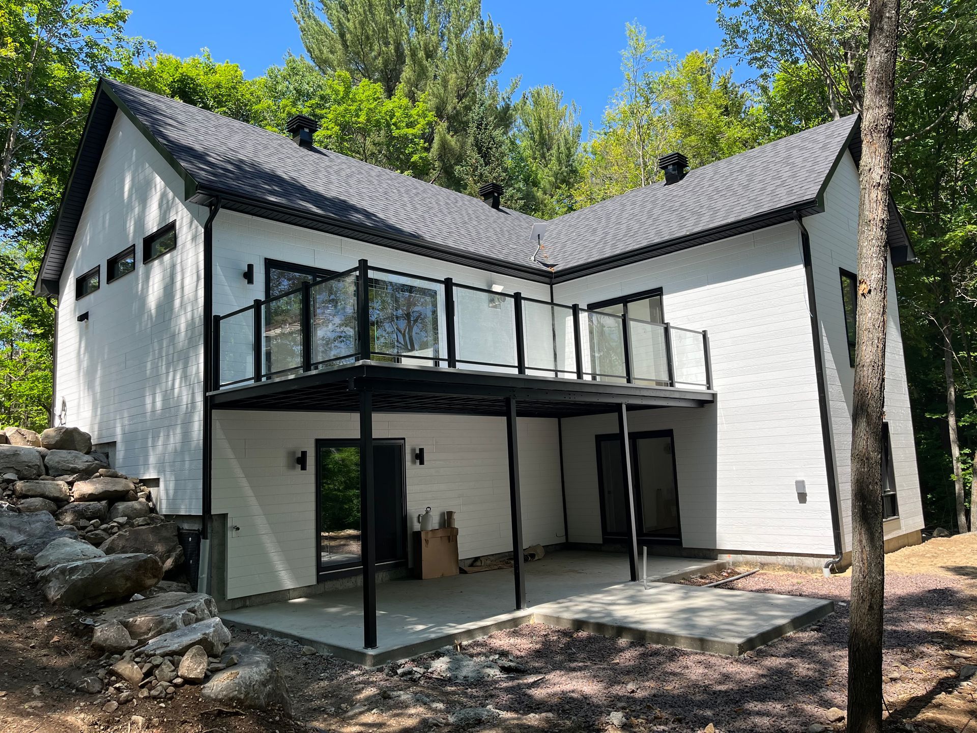 Une maison blanche avec un balcon au milieu des bois.