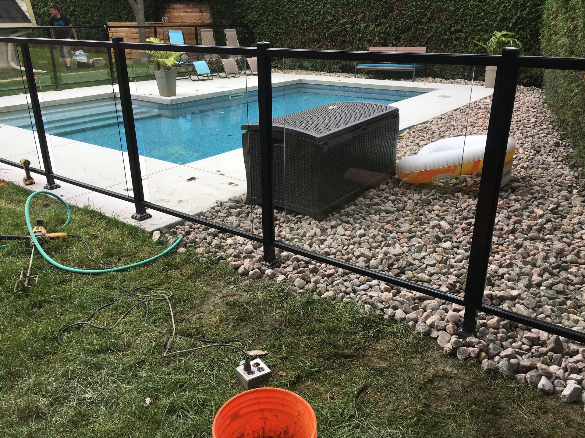 Une clôture entoure une piscine dans une cour arrière.