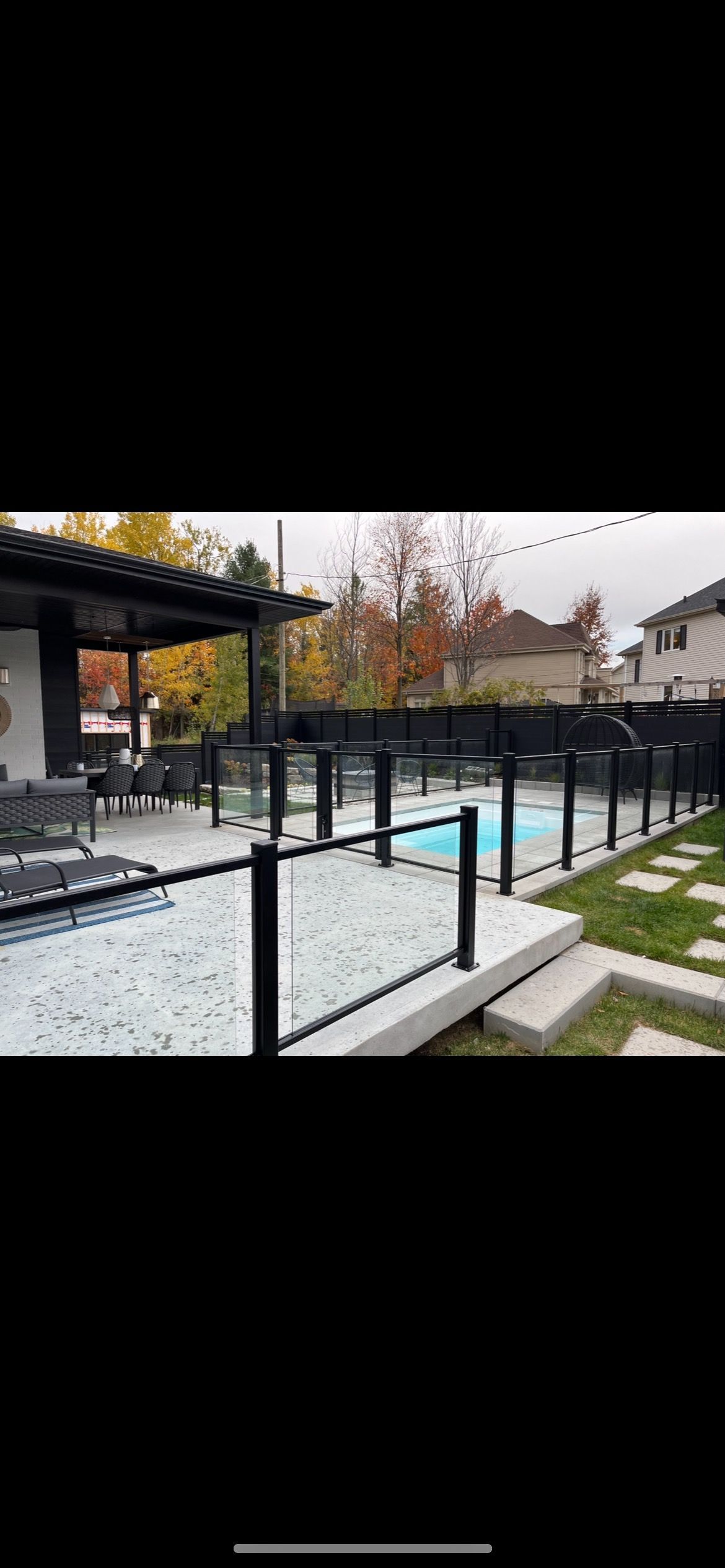 Une cour arrière avec une piscine et une clôture en verre.