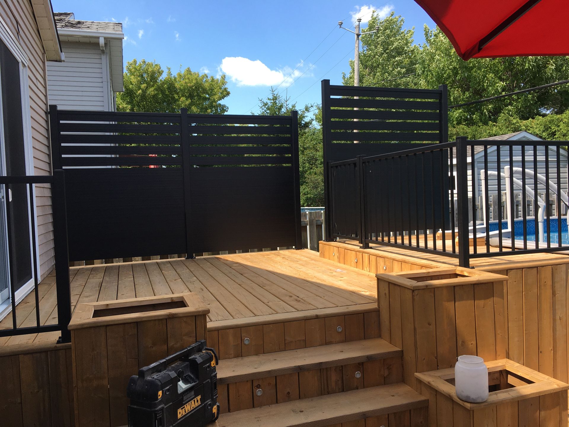 Une terrasse en bois avec une clôture noire et des escaliers