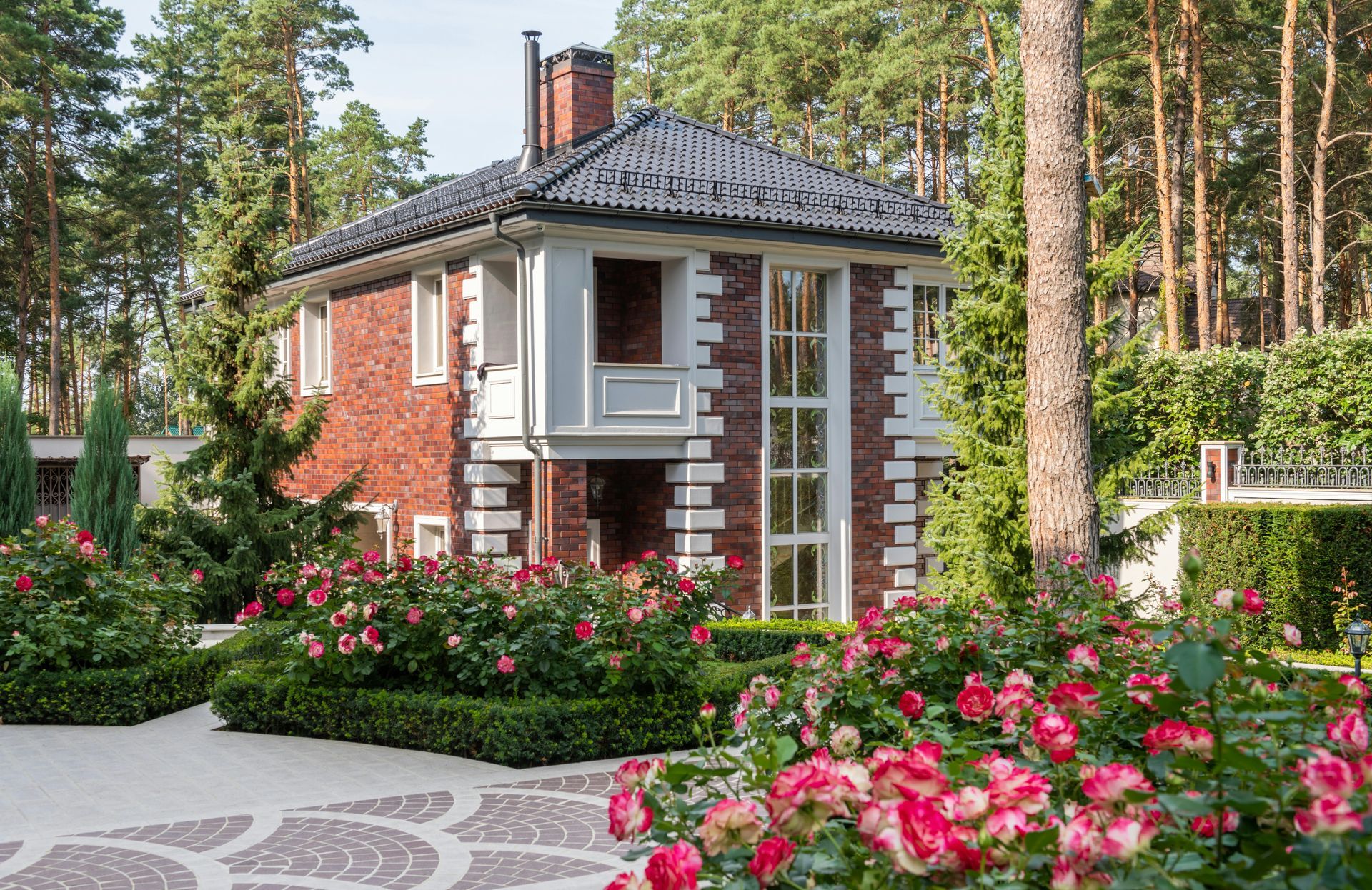 Small brick cottage with a tiled roof, white-framed windows, and flowers in a garden in Central PA