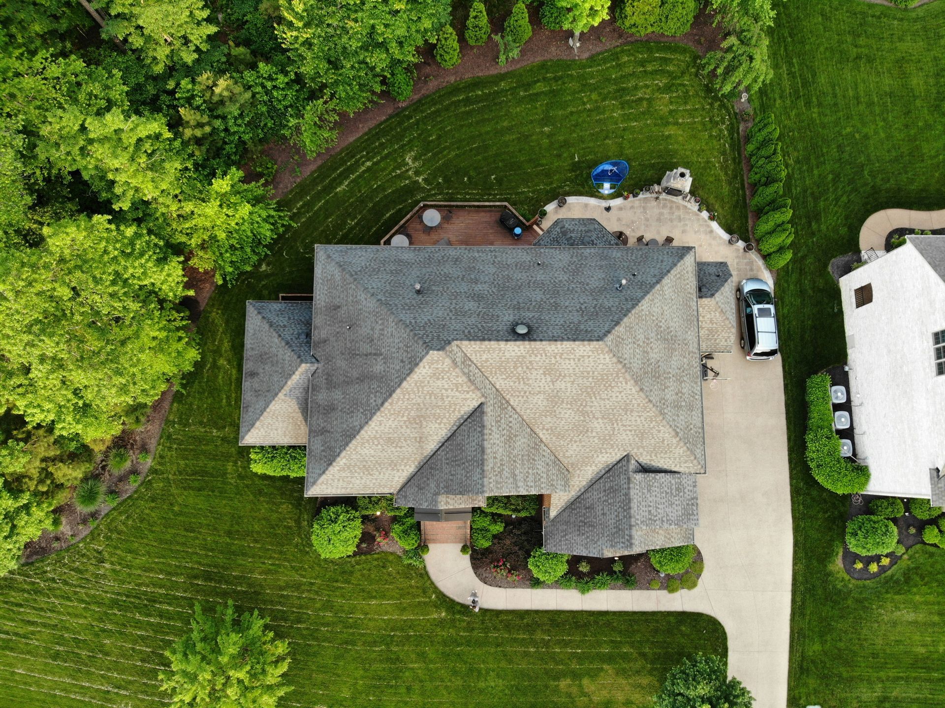 Overhead view of a house with a gray roof and a green lawn. A white car sits in the driveway.