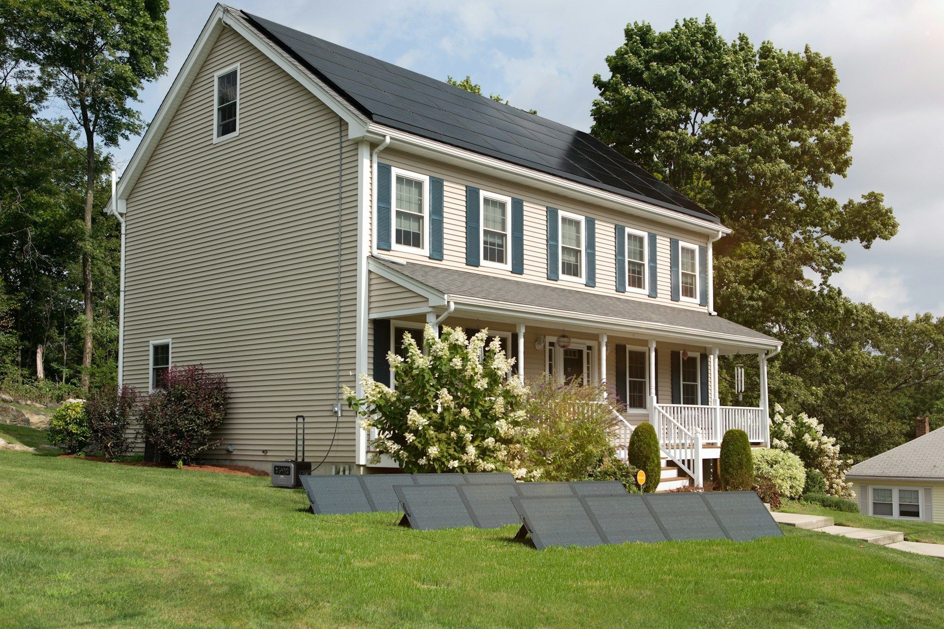 Two-story house with solar panels on the roof and lawn; panels in the foreground.