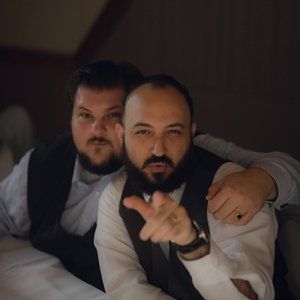 Two men are posing for a picture and one is pointing