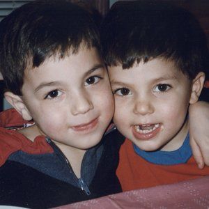 Two young boys are hugging each other and smiling for the camera