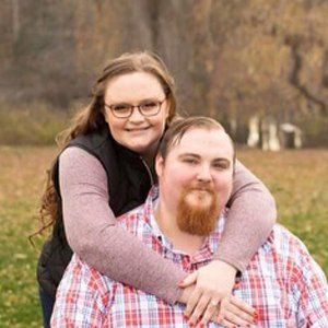 A woman is hugging a man in a plaid shirt.