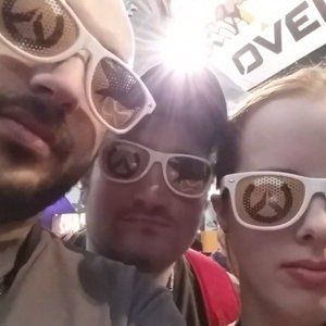 Three people wearing sunglasses are posing for a picture in front of a sign that says love