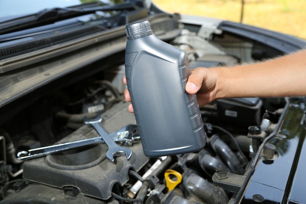 A Person is Pouring Oil Into a Car Engine — North Queensland Independant Fuel Services in Slade Point, QLD