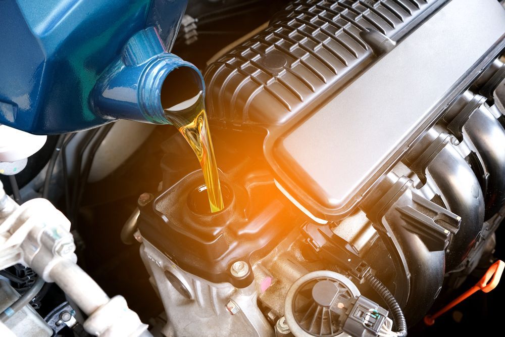 A Person is Pouring Oil Into a Car Engine — North Queensland Independant Fuel Services in Slade Point, QLD