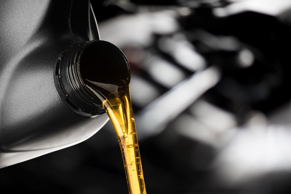 Motor Oil Pouring From a Black Container Into a Car Engine — North Queensland Independant Fuel Services in Mackay, QLD
