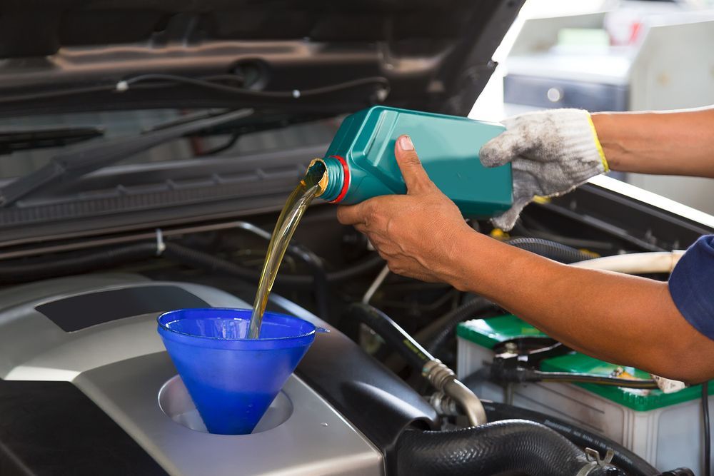 A Person is Pouring Oil Into a Car Engine — North Queensland Independant Fuel Services in Slade Point, QLD