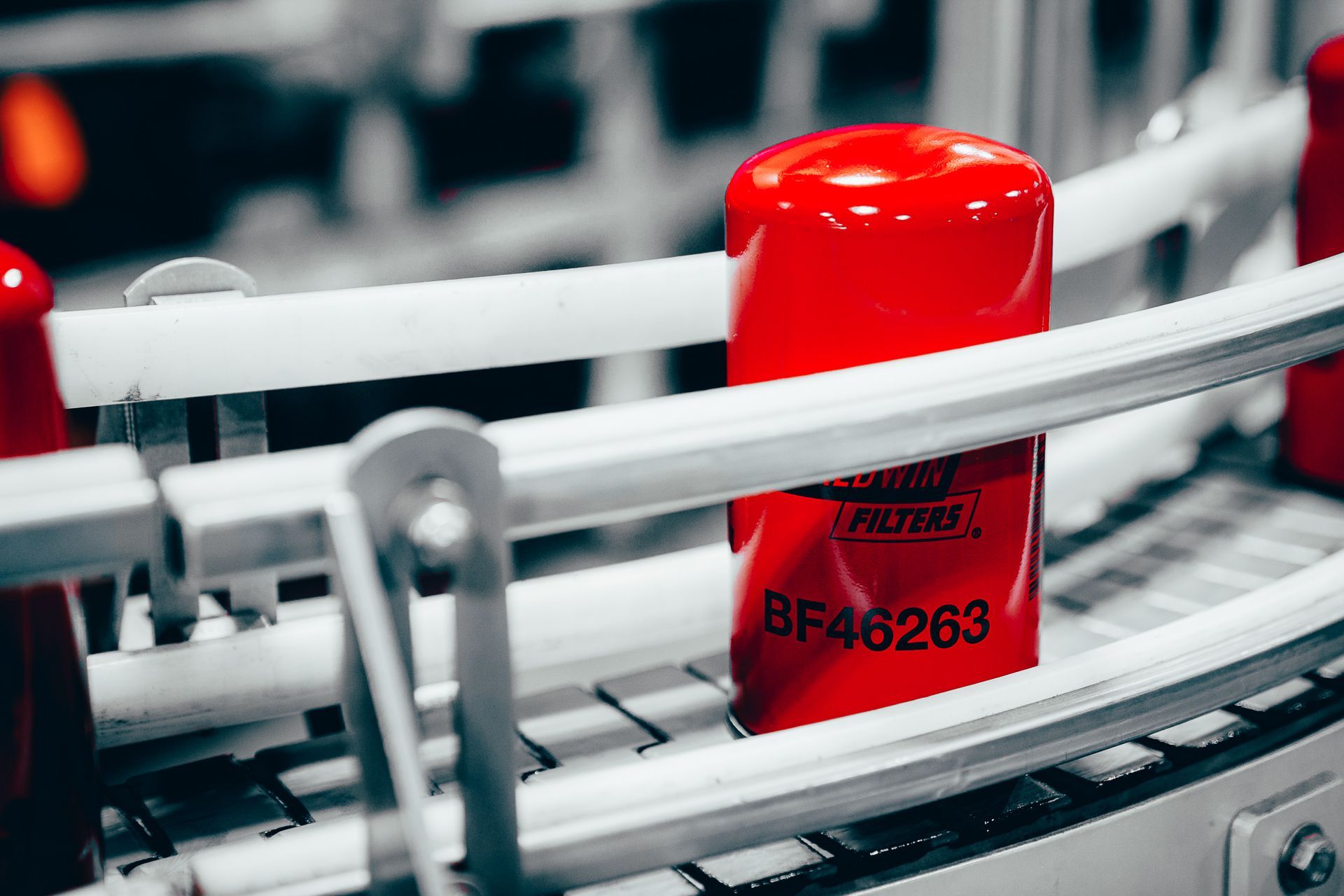 Red oil filter moving on a conveyor belt in a factory.