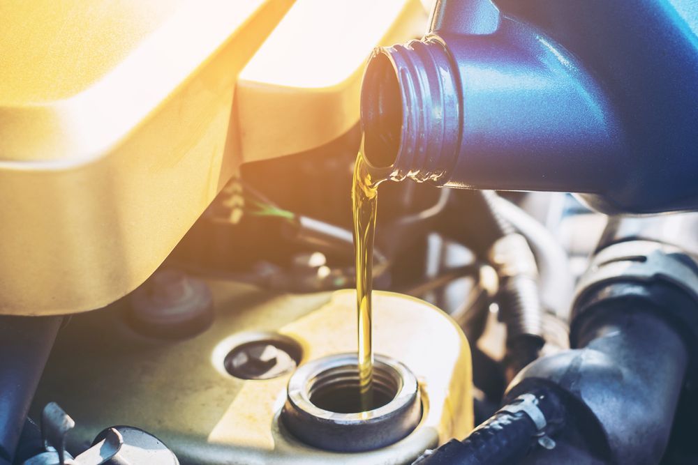 A Person is Pouring Oil Into a Car Engine — North Queensland Independant Fuel Services in Slade Point, QLD