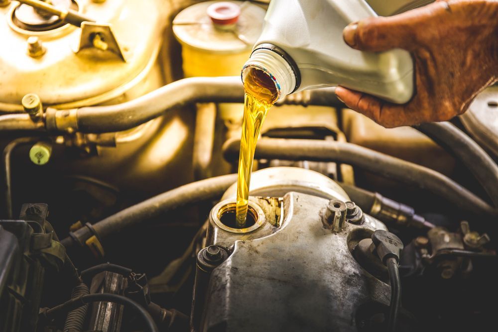 A Person is Pouring Oil Into a Car Engine — North Queensland Independant Fuel Services in Slade Point, QLD