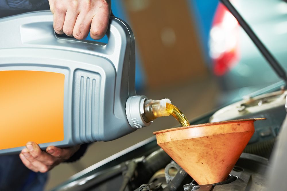 A Person is Pouring Oil Into a Car Through a Funnel— North Queensland Independant Fuel Services in Slade Point, QLD