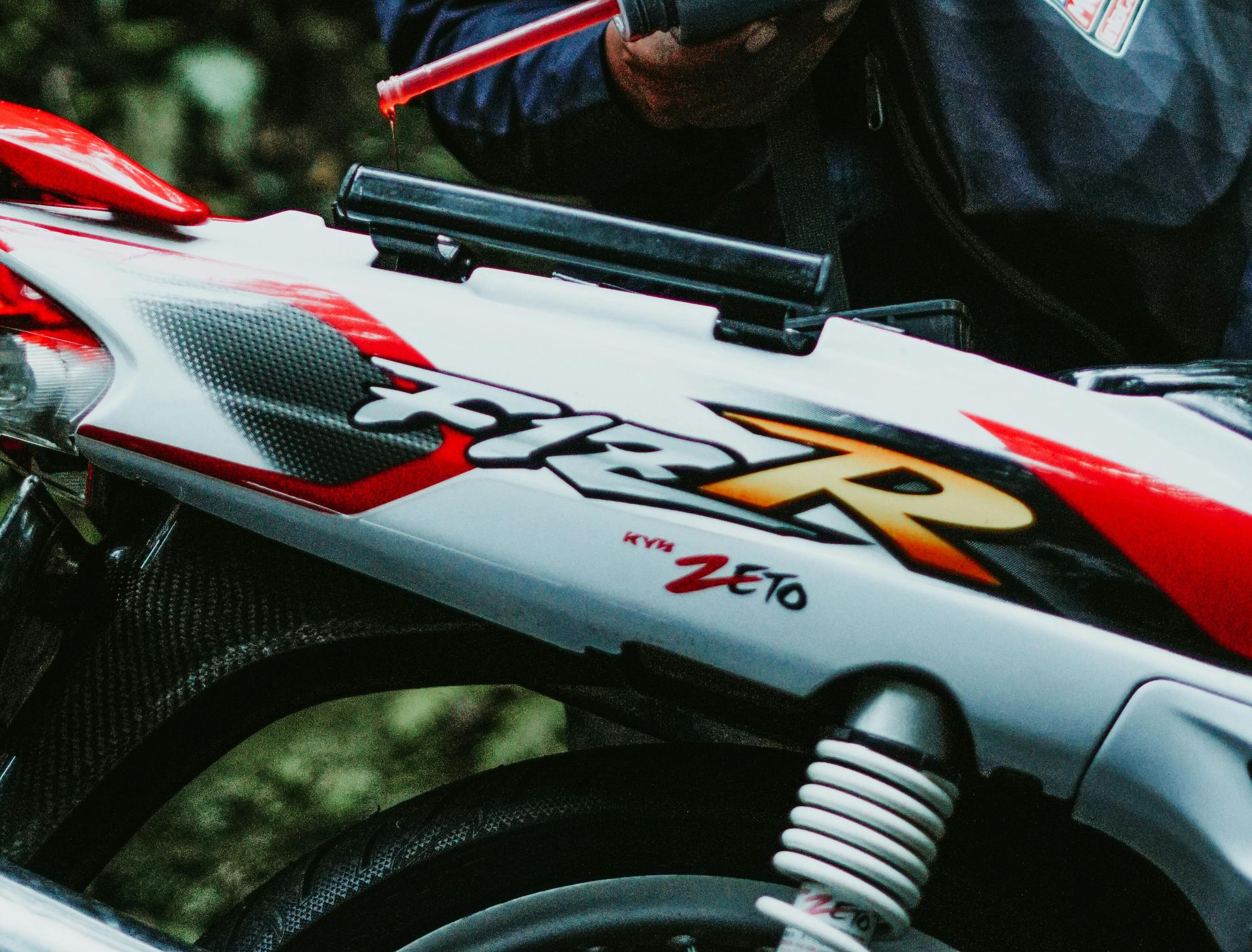 A Man is Pouring Oil Into a Motorcycle Engine — North Queensland Independant Fuel Services in Slade Point, QLD