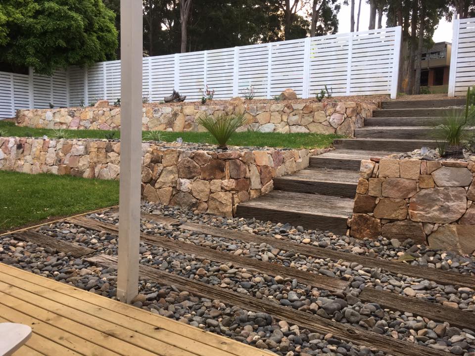 A Wooden Deck With Stairs Leading Up To A Stone Wall — Creative Landscapes Coffs Harbour In Korora, NSW