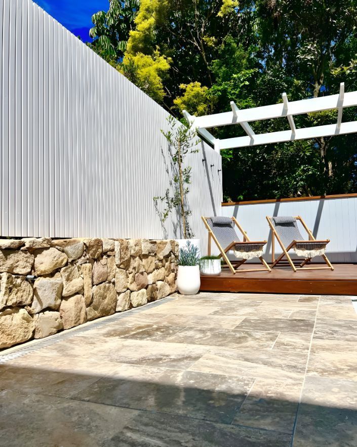 A Patio With Chairs , A Pergola And A Stone Wall — Creative Landscapes Coffs Harbour In Korora, NSW