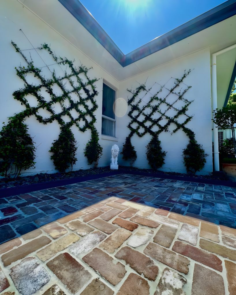 A White House With A Brick Walkway And A Trellis On The Side Of It — Creative Landscapes Coffs Harbour In Emerald Beach, NSW