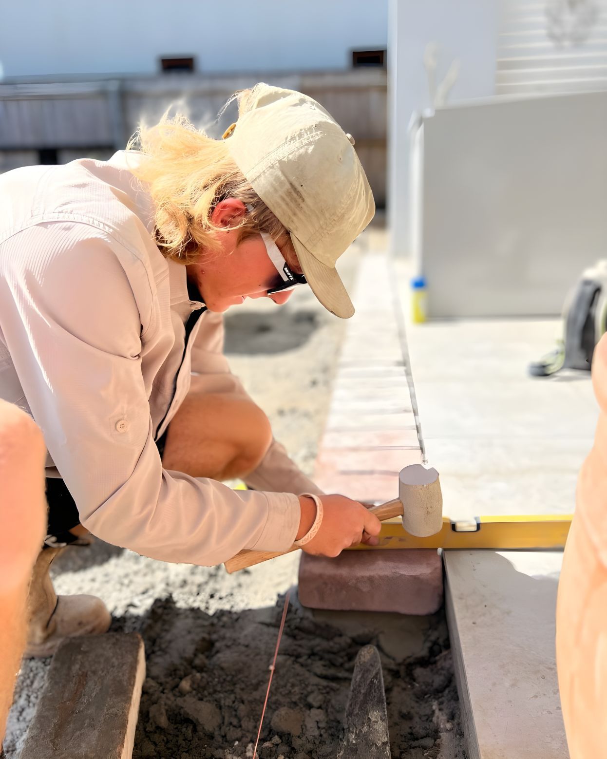 A Woman Is Measuring Bricks With A Ruler And A Hammer — Creative Landscapes Coffs Harbour In Sandy Beach, NSW