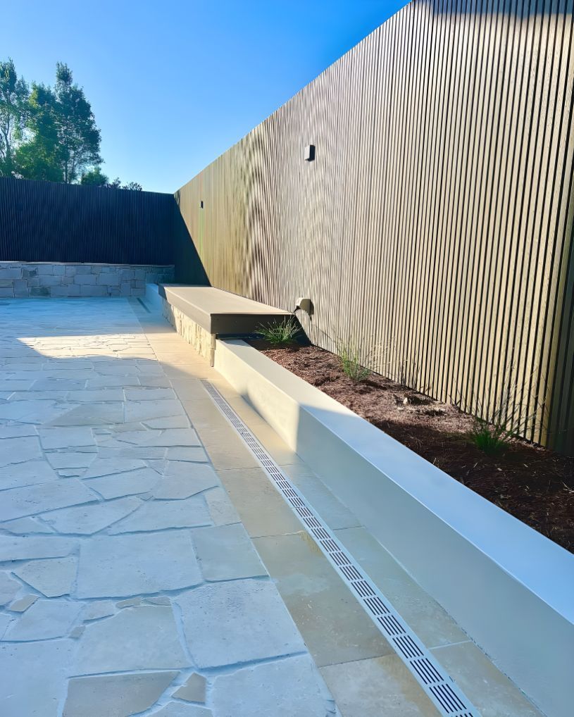 A Stone Walkway With A Bench And A Fence In The Background — Creative Landscapes Coffs Harbour In Korora, NSW