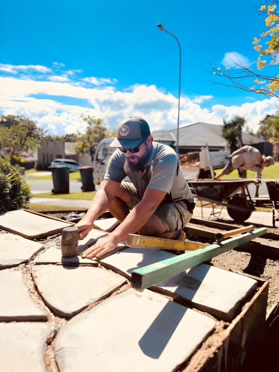 A Man Is Kneeling Down On A Concrete Surface — Creative Landscapes Coffs Harbour In Toormina, NSW