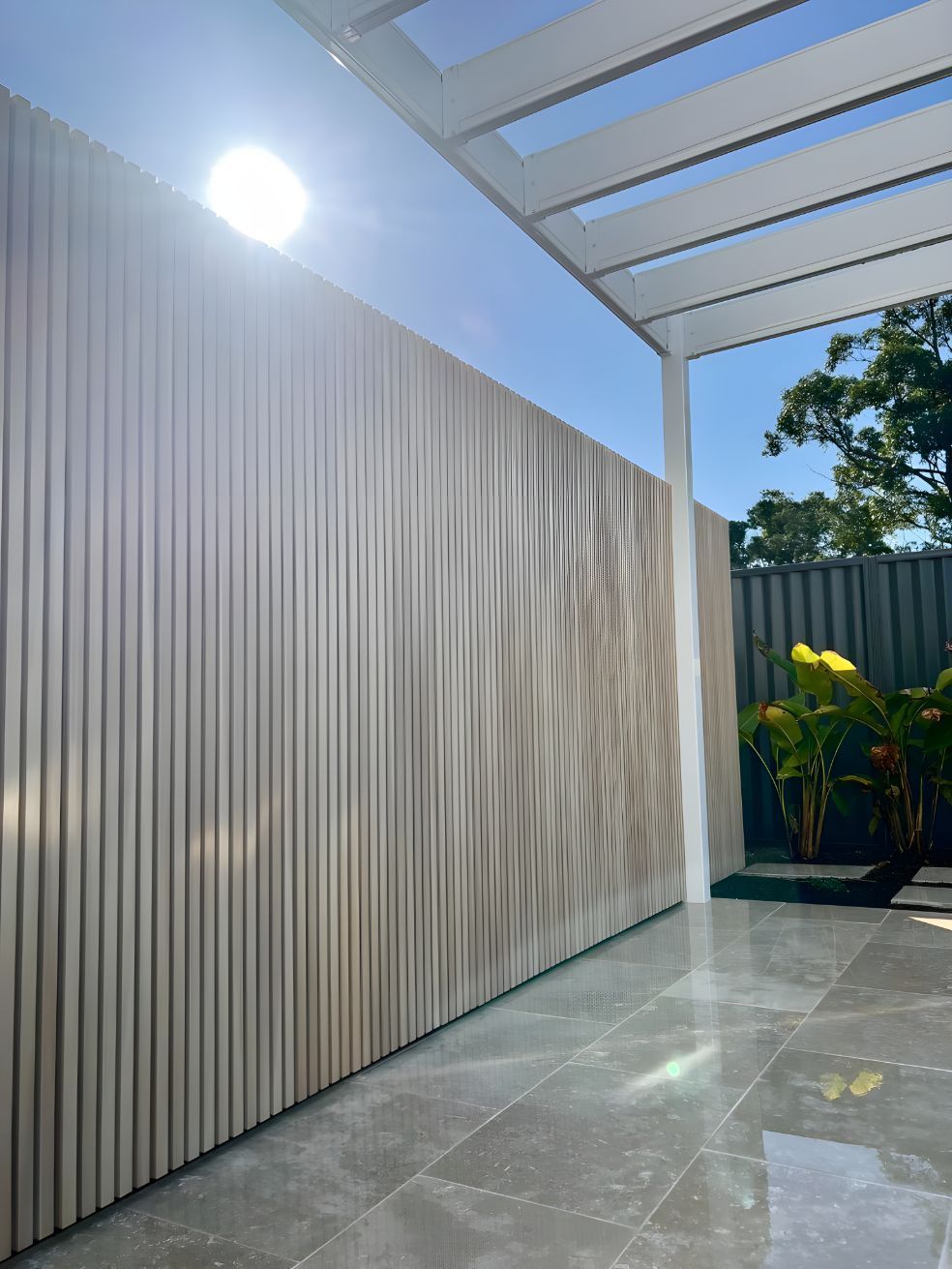 A Wooden Fence Is Surrounded By A Tiled Floor And A Pergola — Creative Landscapes Coffs Harbour In Toormina, NSW