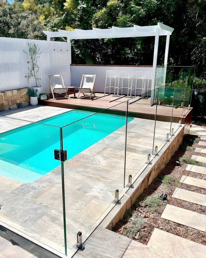 A Large Swimming Pool With A Glass Fence Around It — Creative Landscapes Coffs Harbour In Korora, NSW