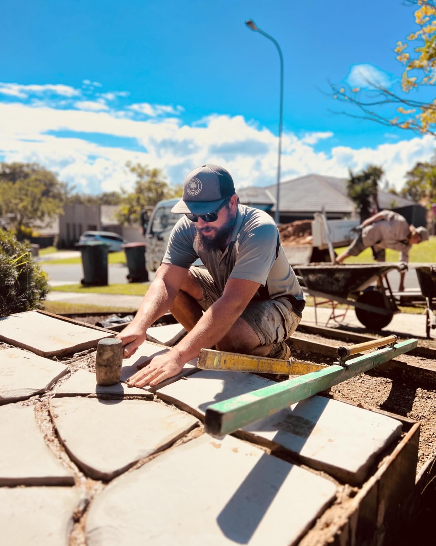 A Man Is Kneeling Down On A Concrete Surface With A Measuring Tape — Creative Landscapes Coffs Harbour In Korora, NSW