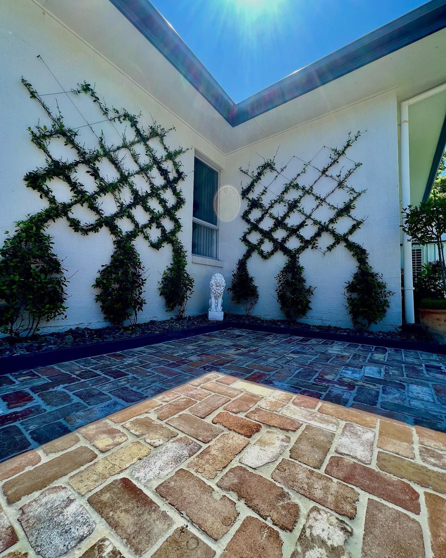 A Brick Patio In Front Of A White House With A Trellis On The Wall — Creative Landscapes Coffs Harbour In Korora, NSW