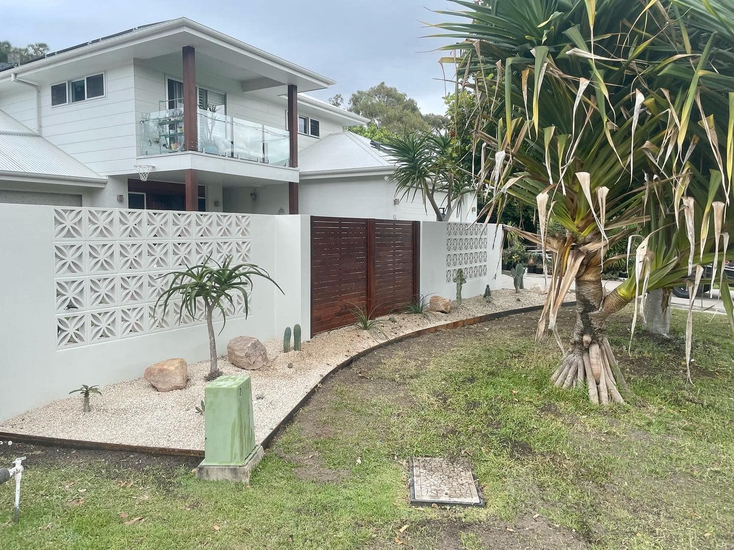A White House With A Fence And A Palm Tree In Front Of It — Creative Landscapes Coffs Harbour In Korora, NSW