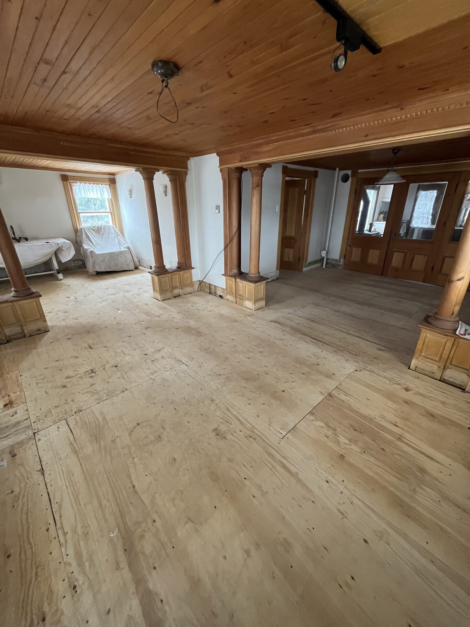 Pièce spacieuse avec parquet, plafond et piliers en bois. La lumière naturelle qui entre par les fenêtres illumine la pièce.