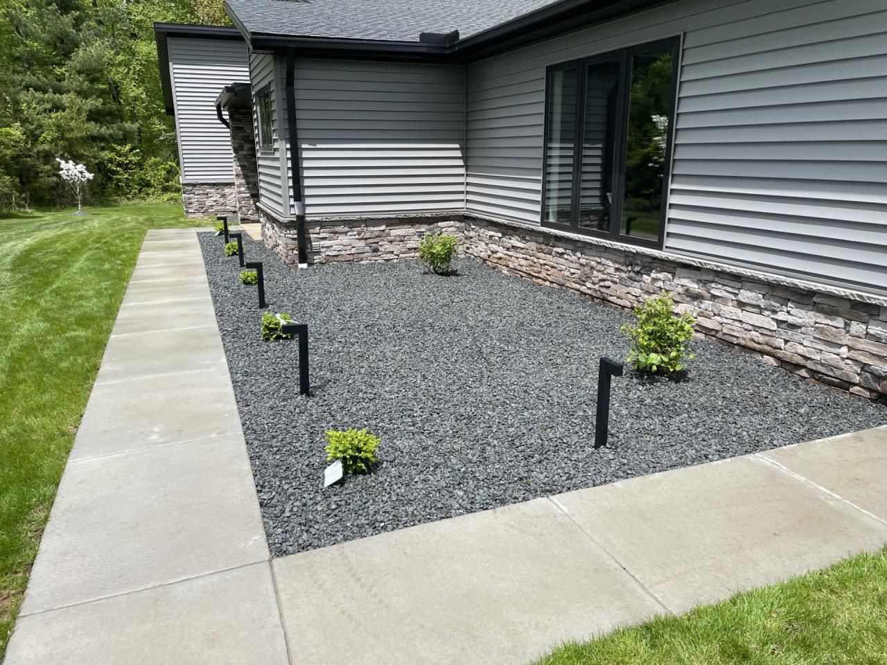 A sidewalk leading to a house with a gravel garden in front of it.