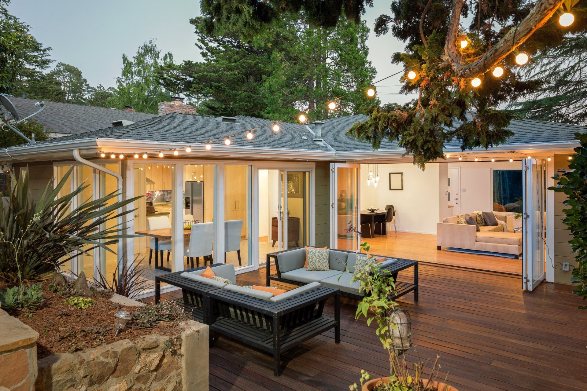 A patio with a couch , table and chairs in front of a house.