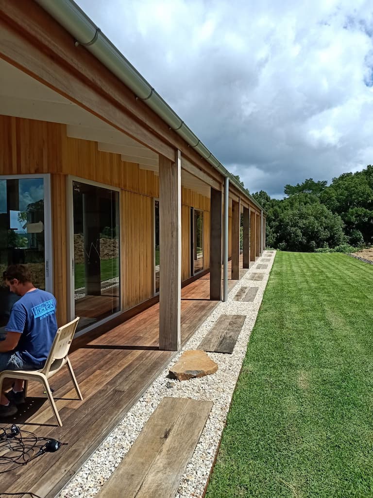 Man Sitting on Porch of Large Modern House — Electricians in Byron Shire