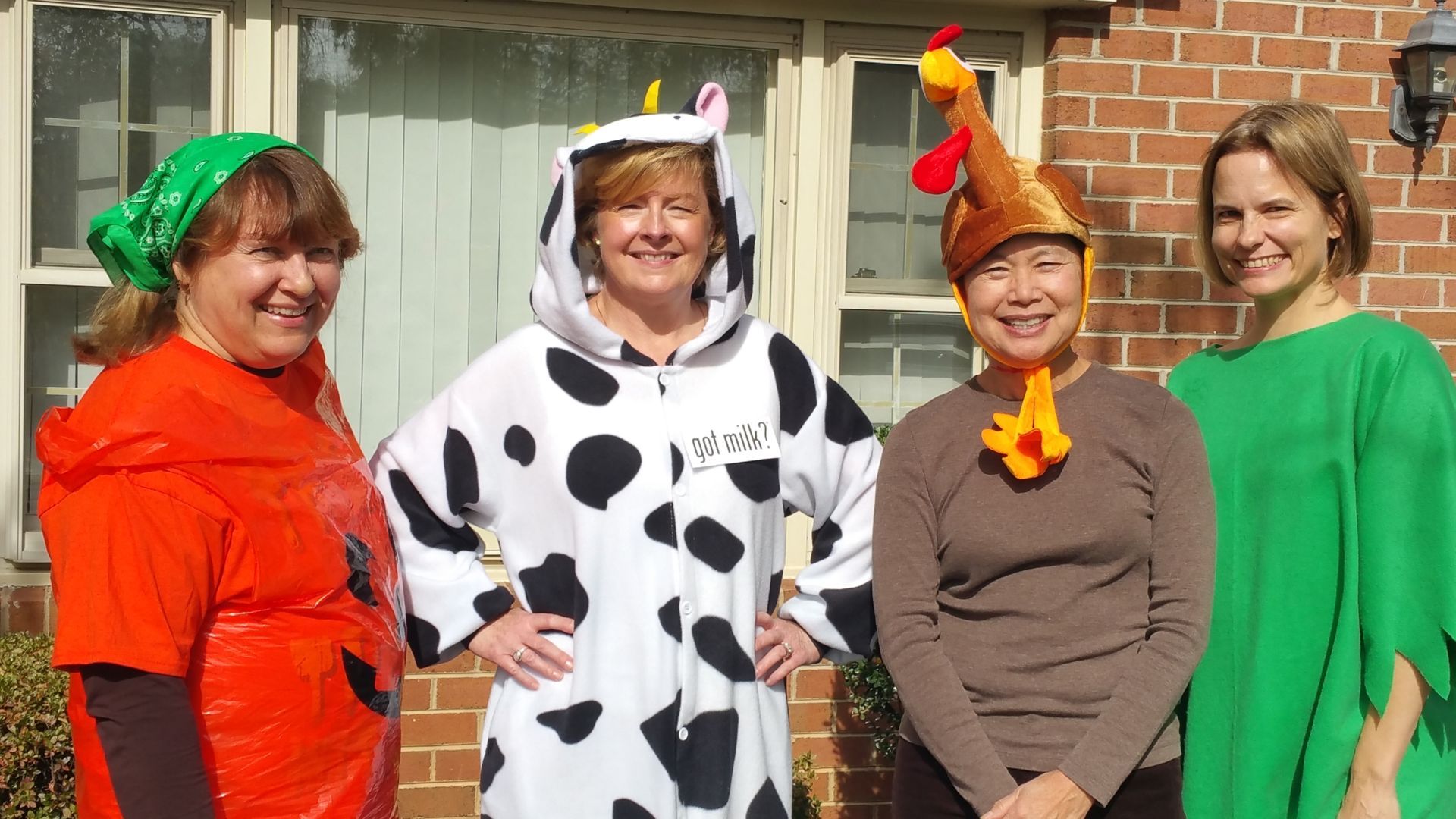 A group of women are posing for a picture while wearing cow and chicken costumes.