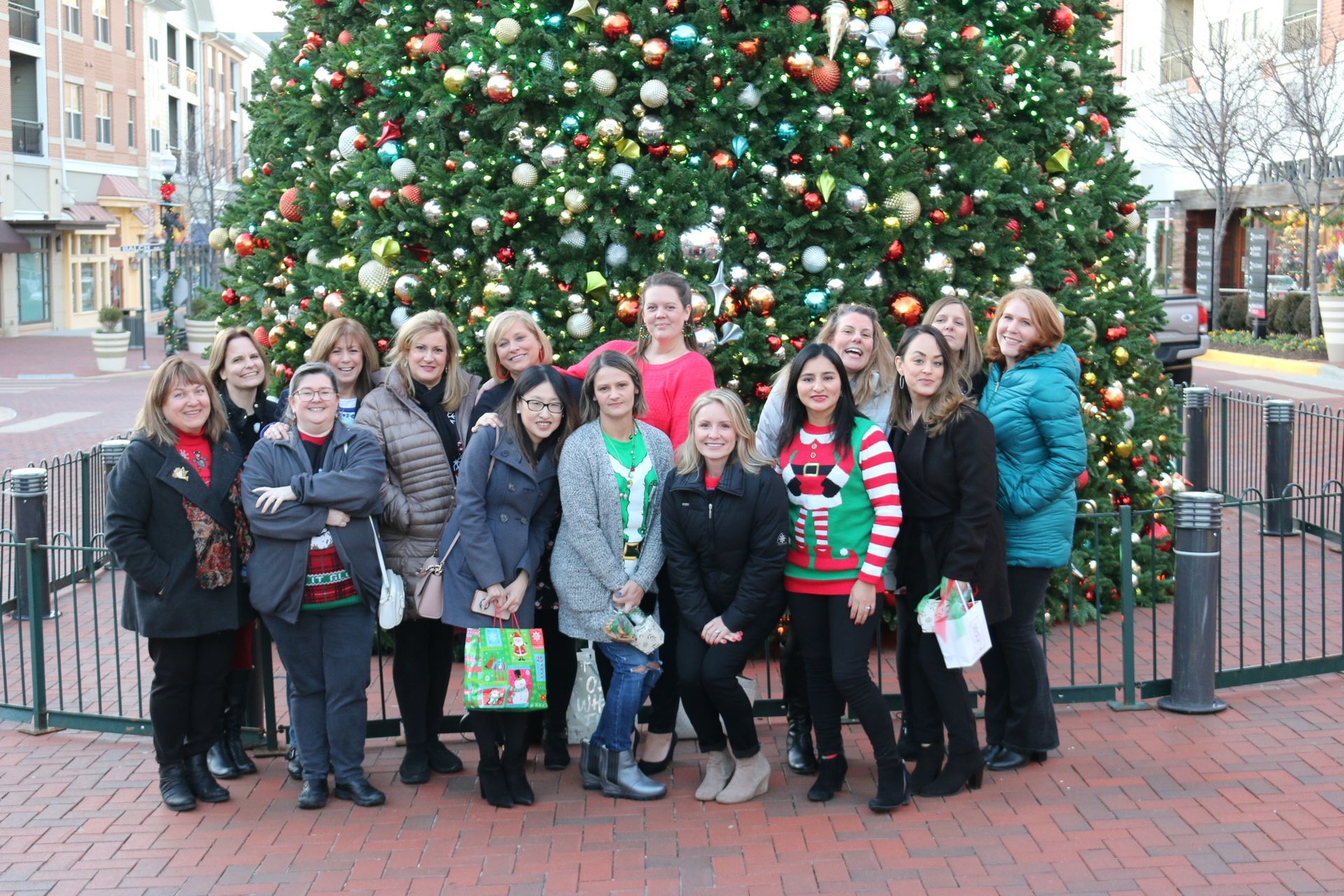 A group of women are posing for a picture in front of a christmas tree.