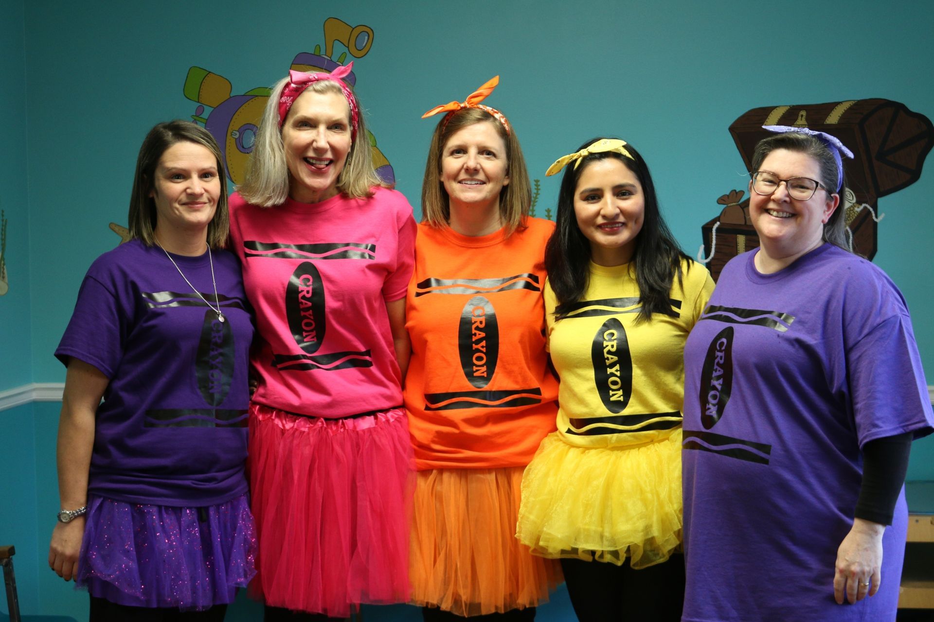 A group of women dressed in crayon costumes are posing for a picture.