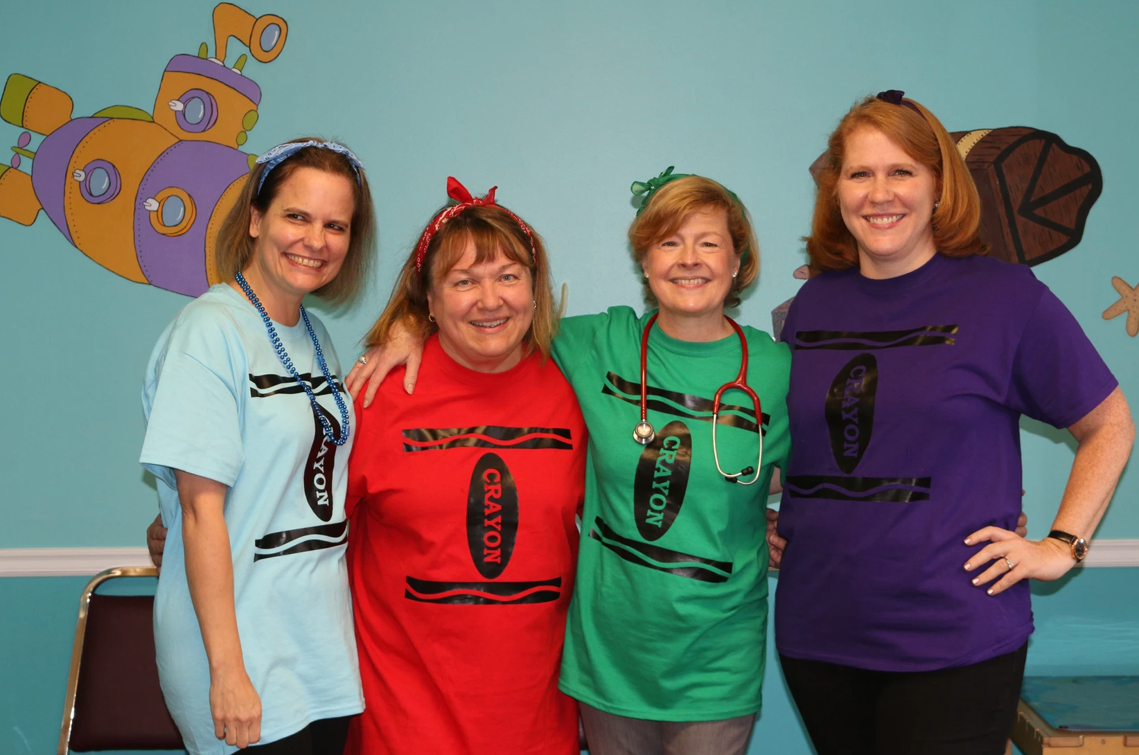 Four women wearing crayon shirts pose for a picture