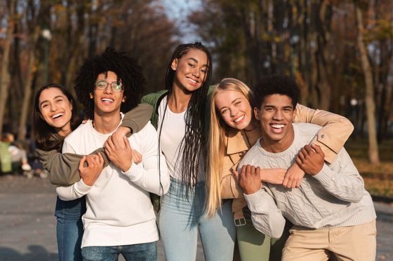 A group of young people are posing for a picture in a park.