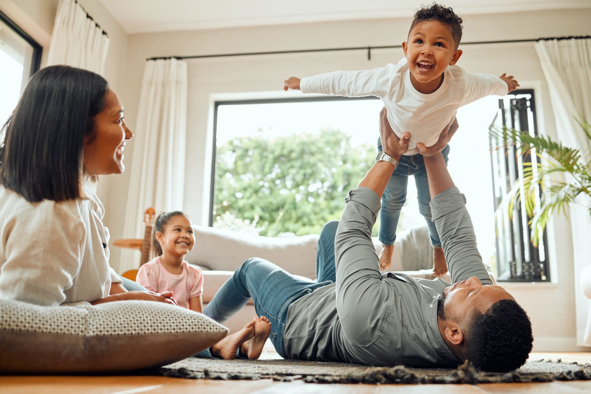 A man is laying on the floor holding a child in the air.