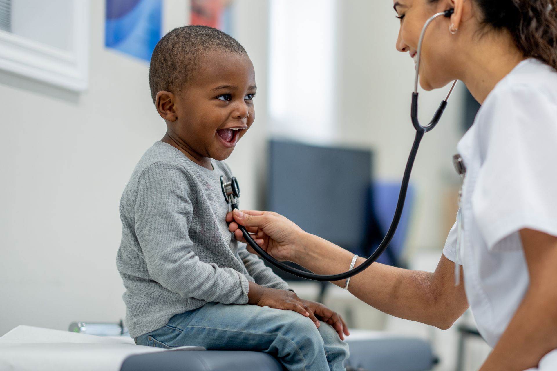 A nurse is listening to a young boy 's heartbeat with a stethoscope.