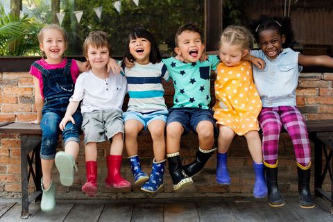 Smiling children sitting on a park bench.