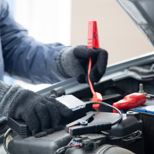 A person is charging a car battery with a jump starter