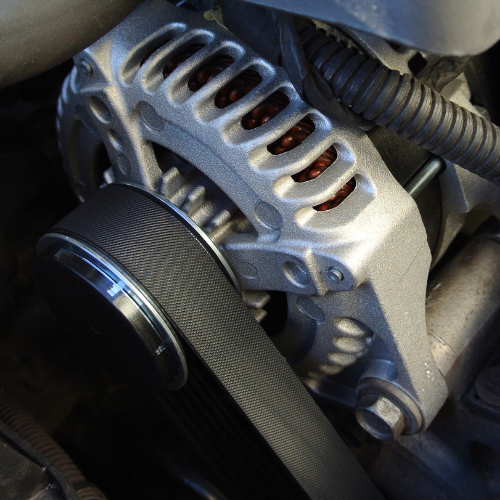 A close up of a car alternator with a belt attached to it