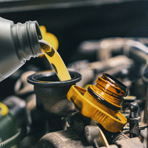 A bottle of oil is being poured into a car engine