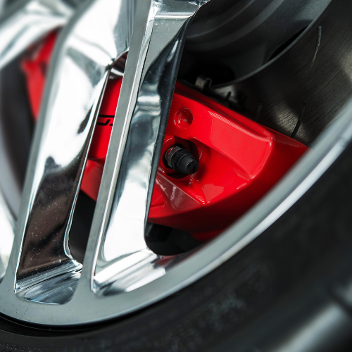 A close up of a car wheel with a red brake caliper