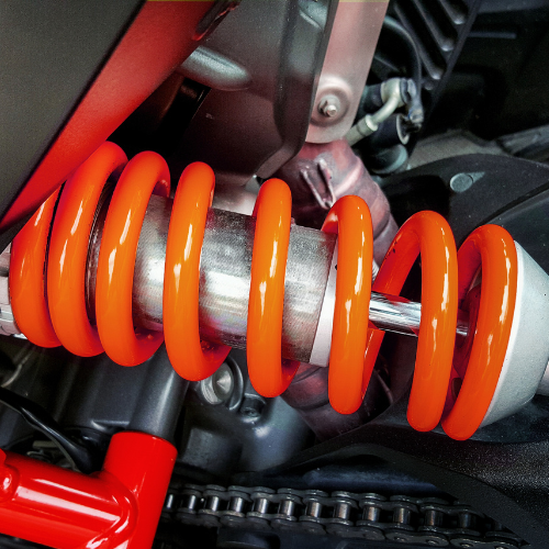 A close up of an orange spring on a motorcycle