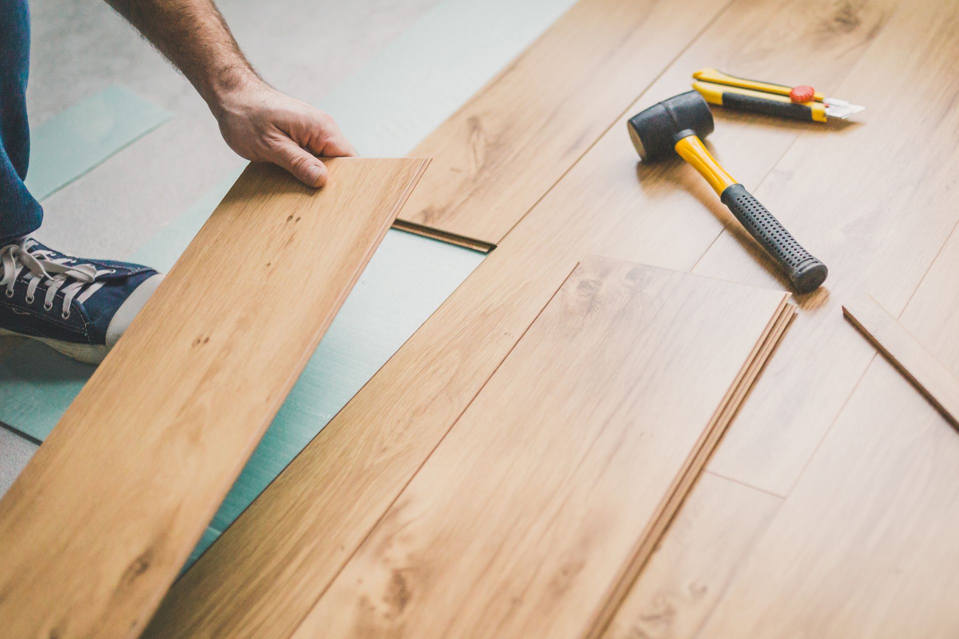 Hands measuring wooden planks with a ruler and hammer on a tabletop
